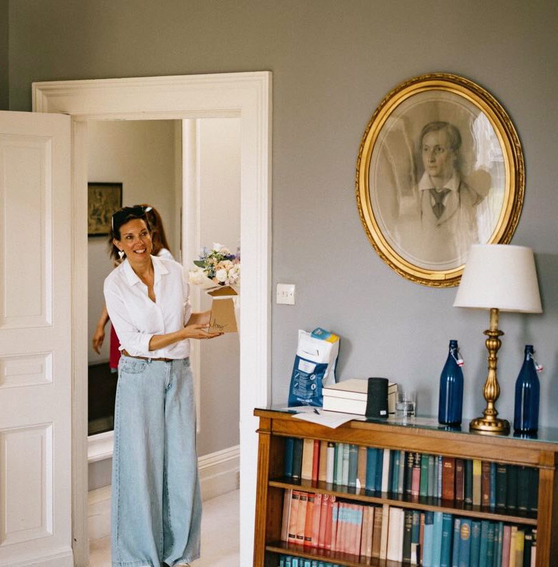 Vicki from Wonderland Blooms delivering wedding flowers in Yorkshire, smiling while carrying a bouquet arrangement.
