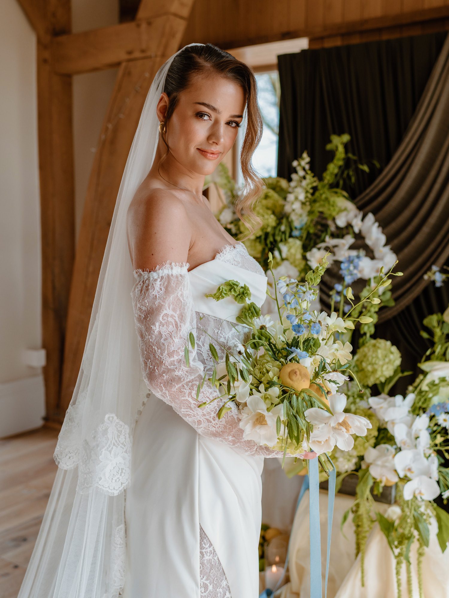Bride holding an elegant white and green wedding bouquet with soft blue accents.